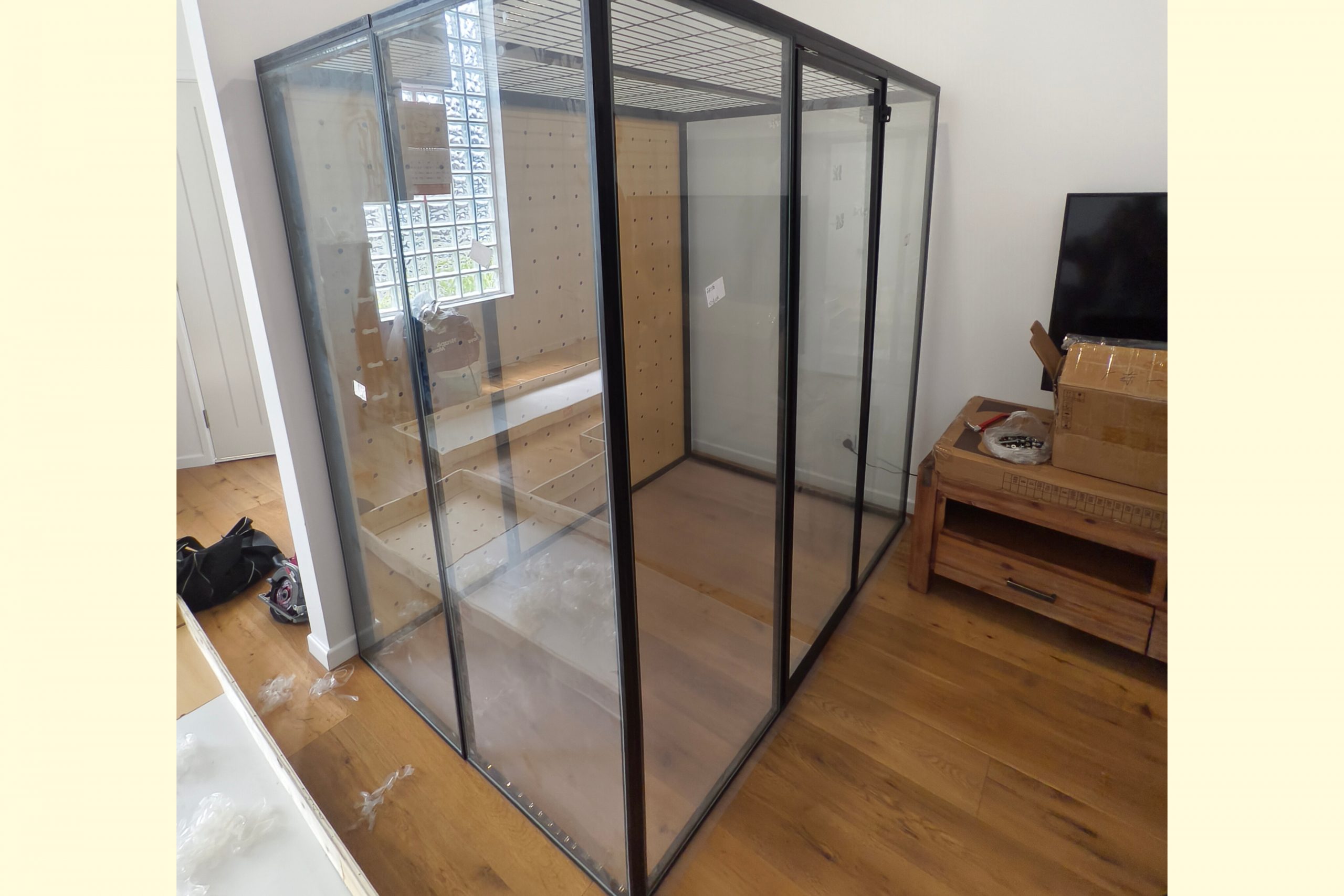 Installation of a custom-built, large indoor glass and black metal frame cat enclosure by Paradise Handyman.